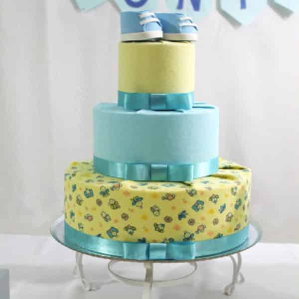 Bolo de chá de bebê amarelo e azul com sapatinho feito de EVA no topo